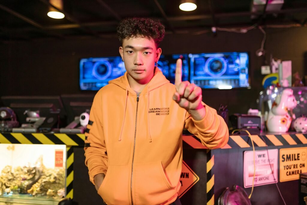 A confident young gamer poses in a gaming venue with futuristic screens behind.