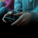 Close-up of hands holding a video game controller, focused in an indoor setting.
